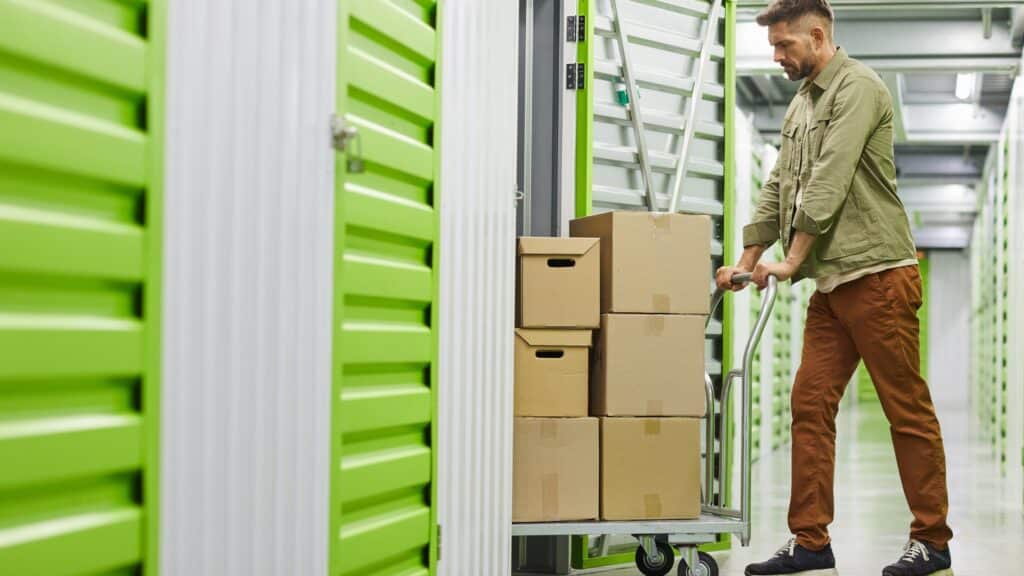 a man pushing a cart with boxes in a climate-controlled storage unit